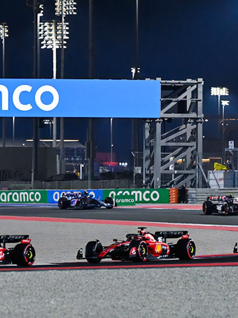 Formula 1 cars racing at night on the Qatar circuit.