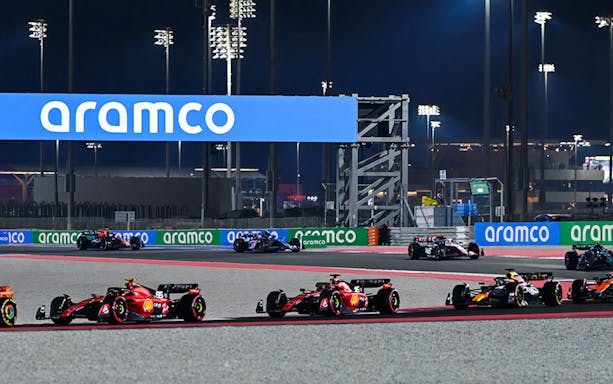 Formula 1 cars racing at night on the Qatar circuit.