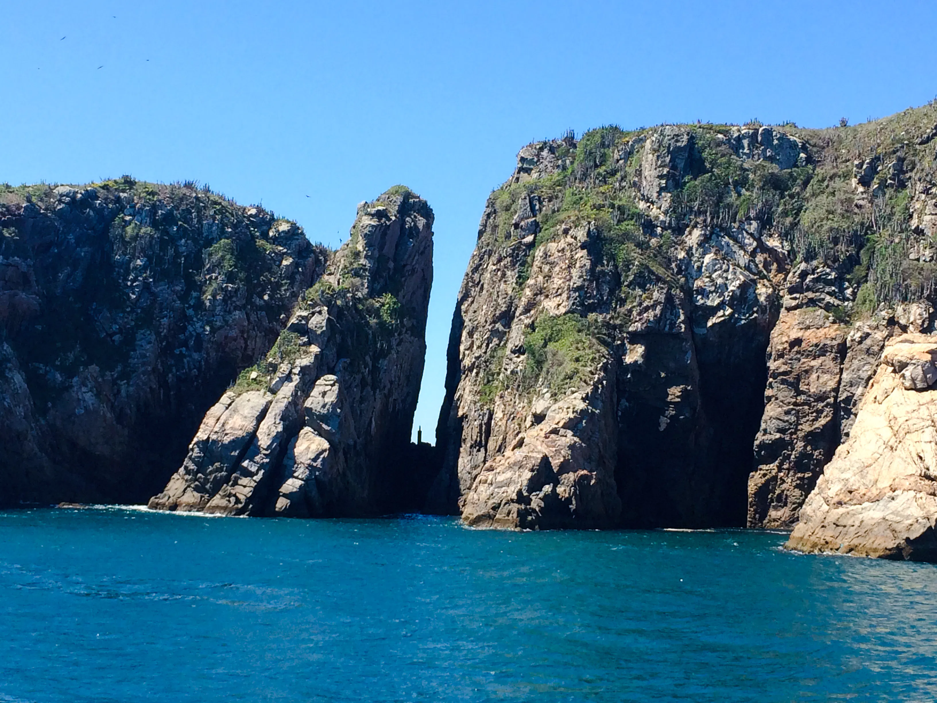 Rock formations at Arraial do Cabo, Brazil, with clear blue ocean.