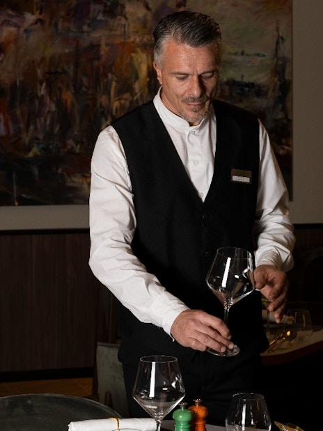 Waiter polishing wine glasses at Plaza Premium First lounge, Fiumicino Airport Terminal 1.