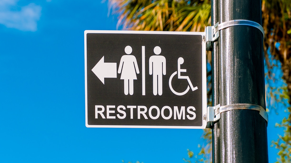 Restroom sign with male, female, and wheelchair symbols on a pole.