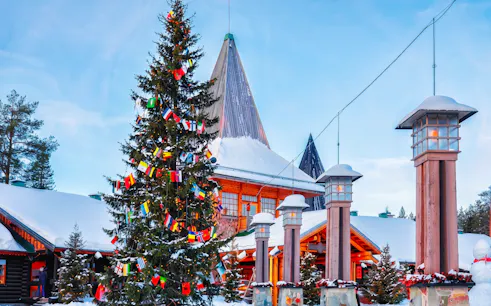 Santa Claus Village in Rovaniemi with snow-covered buildings and a decorated Christmas tree.