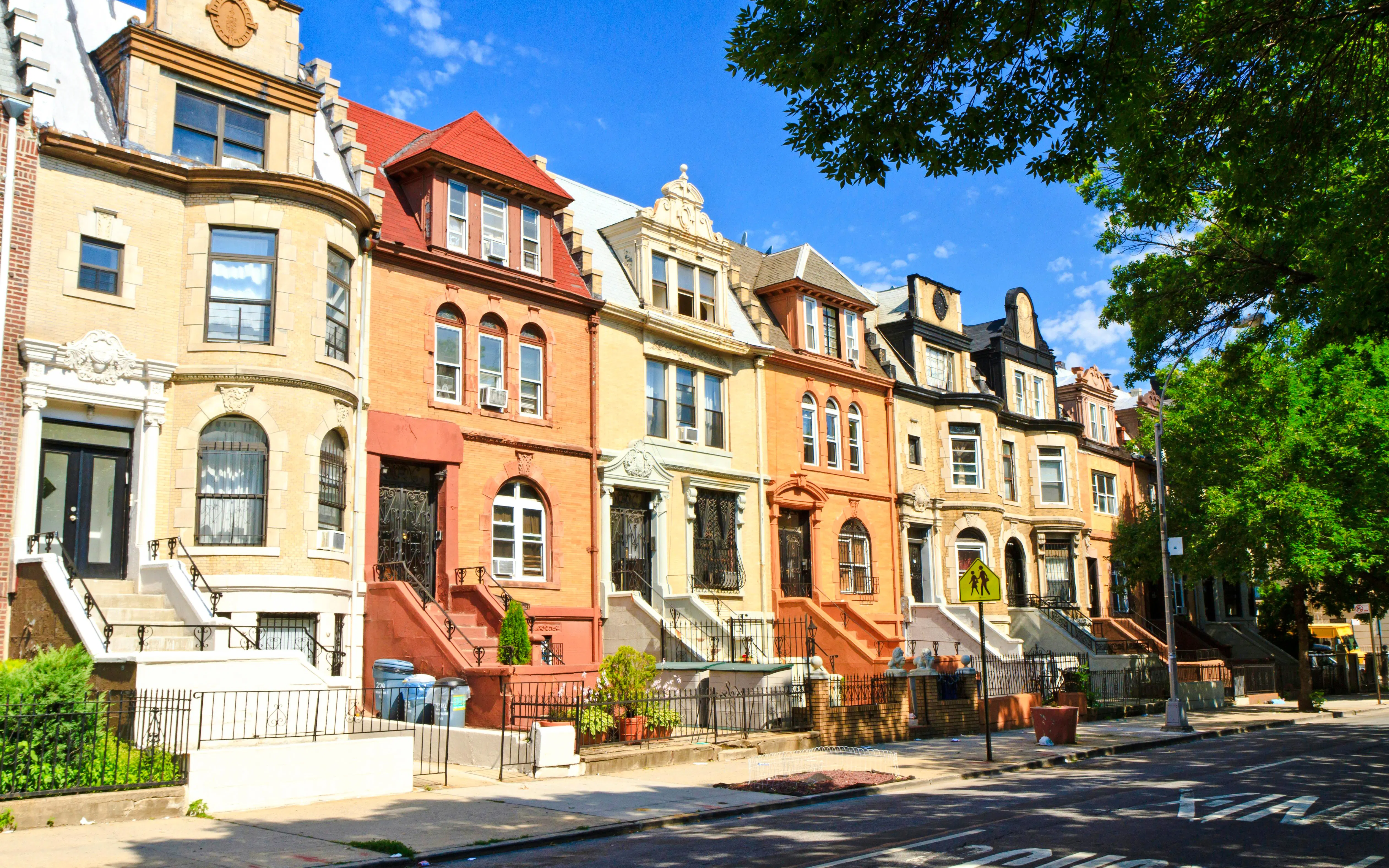 Crown Heights Brooklyn townhouses with classic architecture under a clear blue sky.