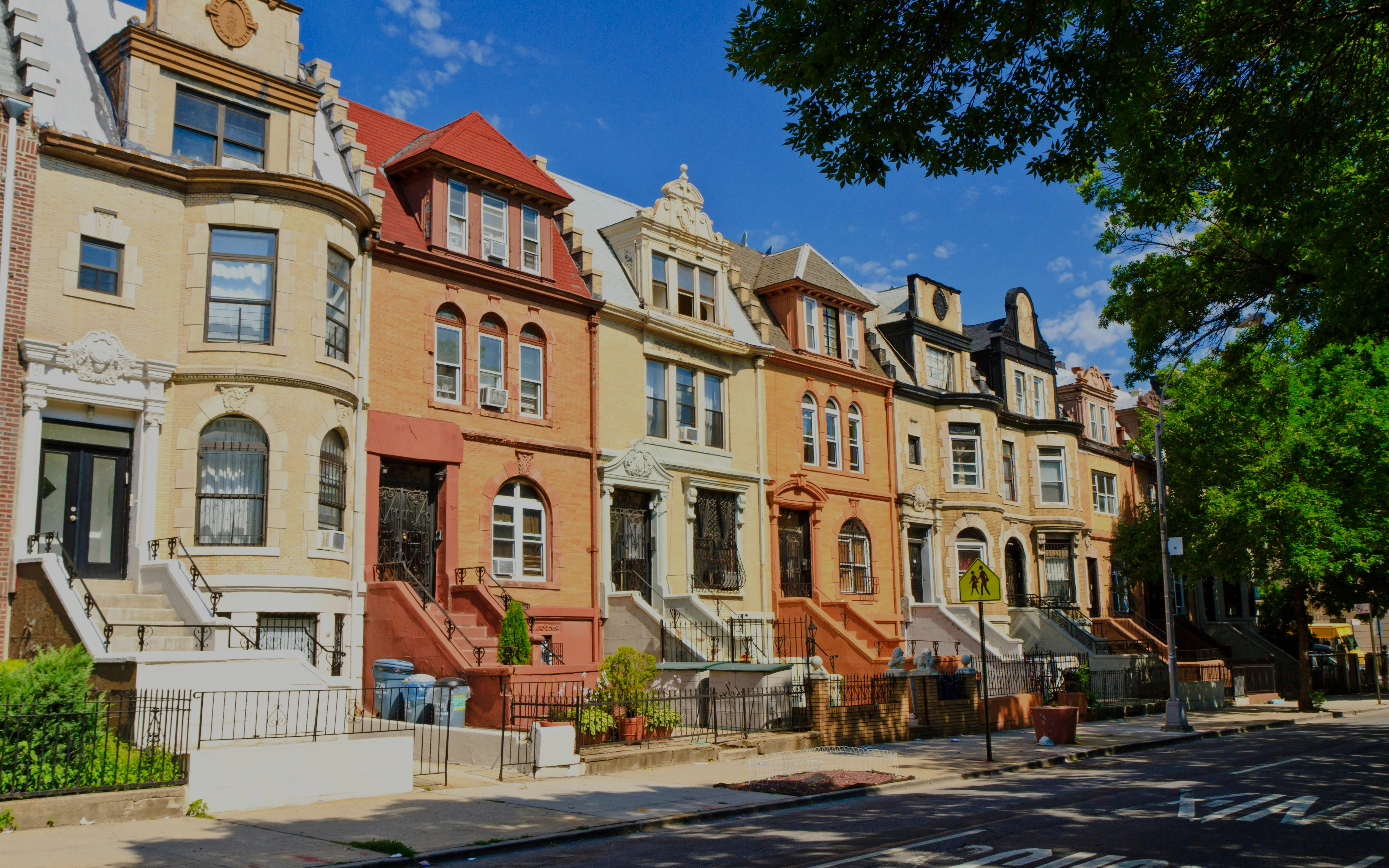 Crown Heights Brooklyn townhouses with classic architecture under a clear blue sky.