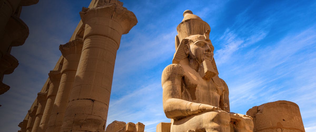 Statue of Ramses II at Luxor Temple, Egypt, with ancient columns.