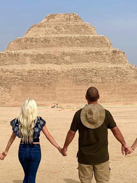 Tourists holding hands in front of the Step Pyramid at Saqqara, Egypt.