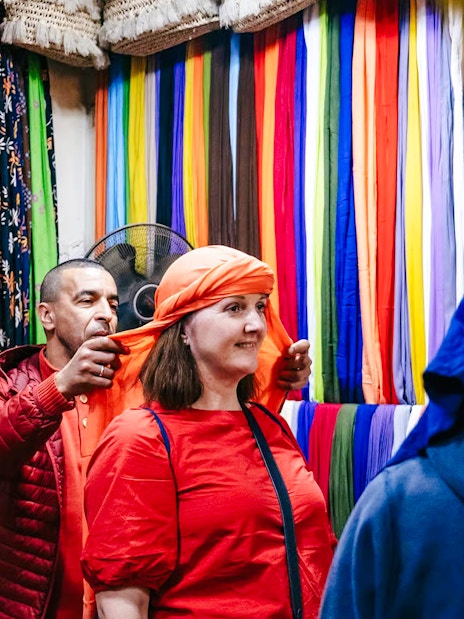 Shopper trying on headscarf in Marrakech souk during private shopping tour.