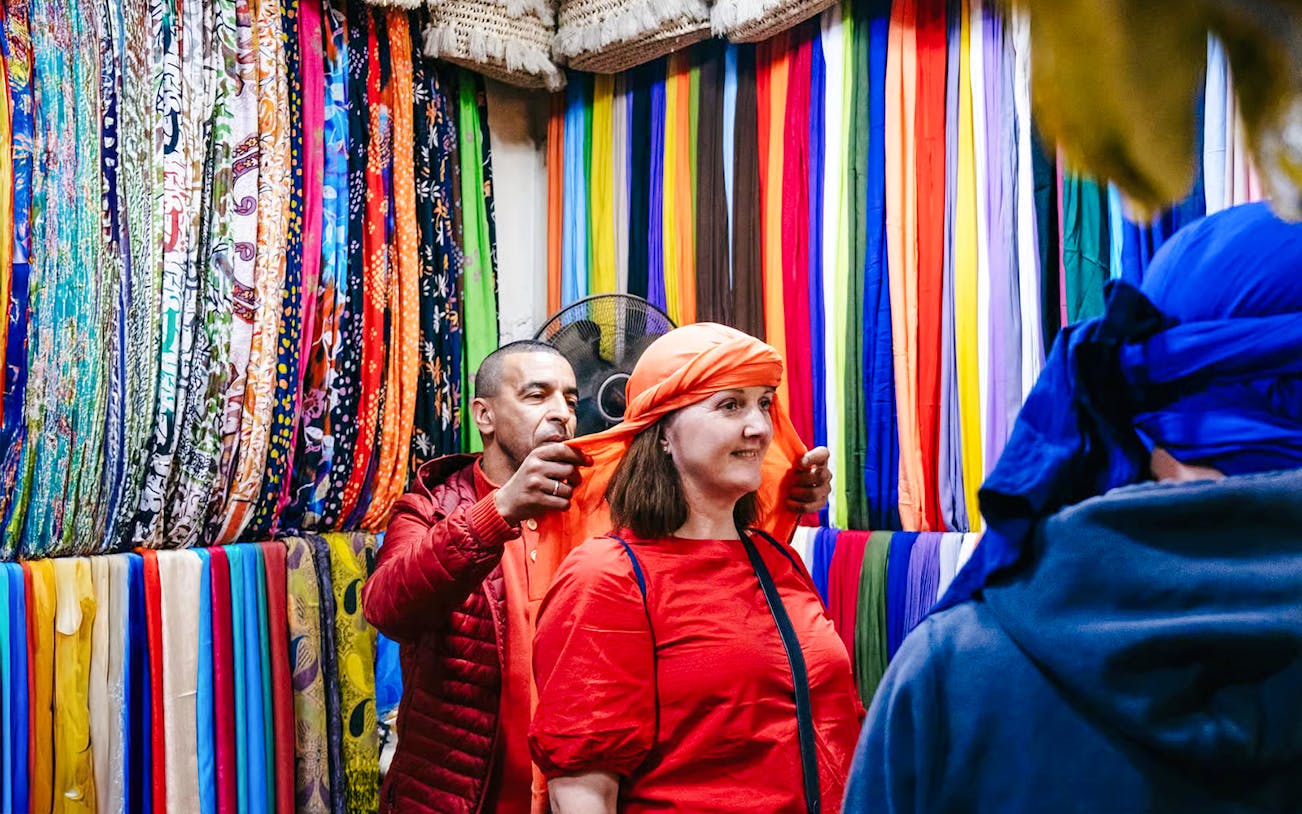 Shopper trying on headscarf in Marrakech souk during private shopping tour.