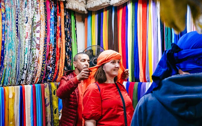 Shopper trying on headscarf in Marrakech souk during private shopping tour.