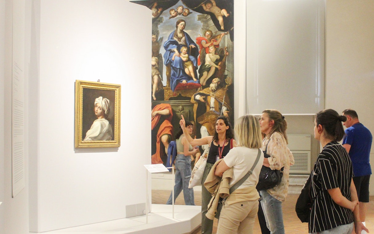Visitors observing art during a guided tour at Palazzo Barberini, Rome.