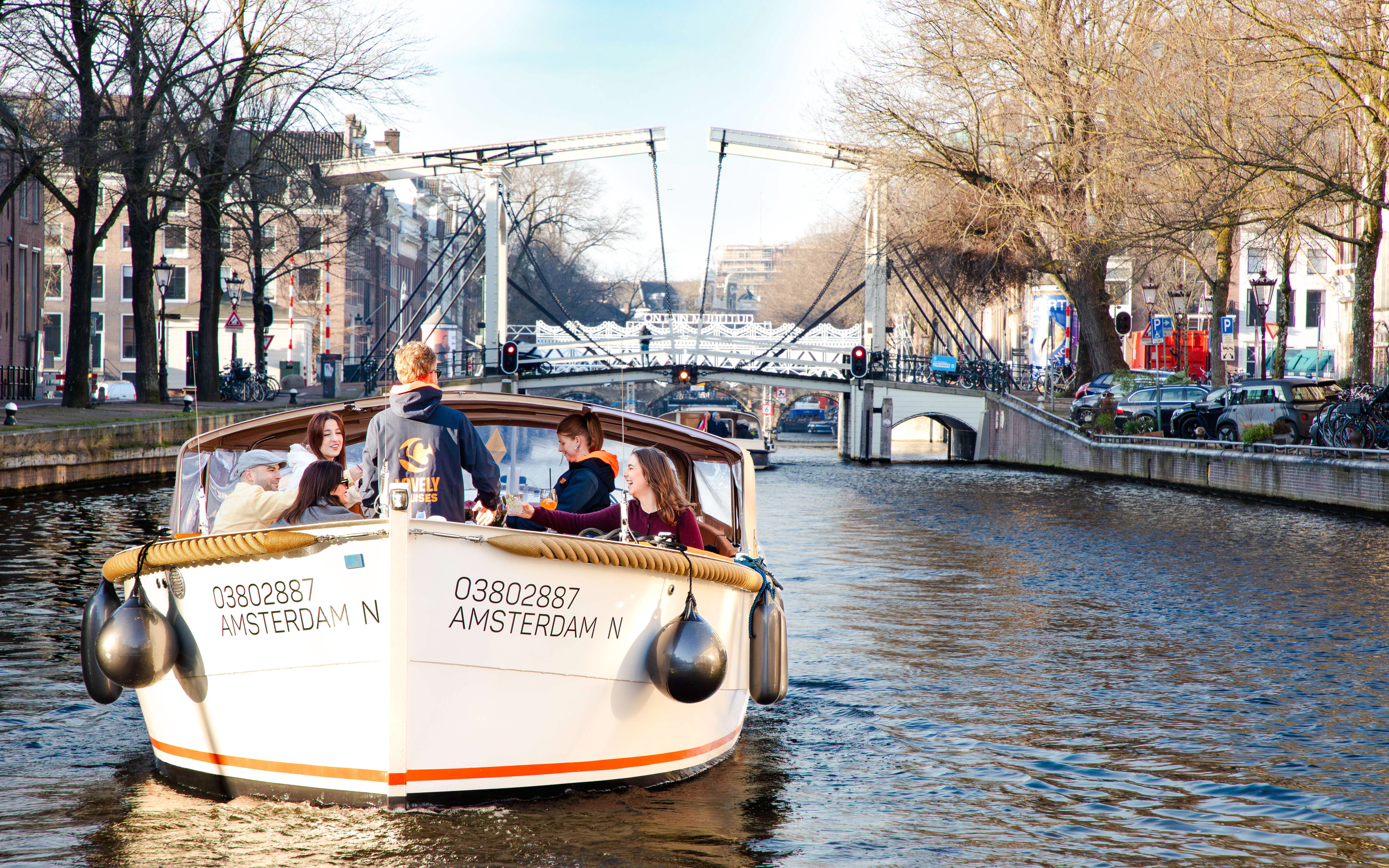 Open boat cruise on Amsterdam canal with people enjoying the view of a drawbridge.