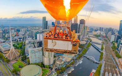 Hot air balloon over Melbourne cityscape at sunrise.