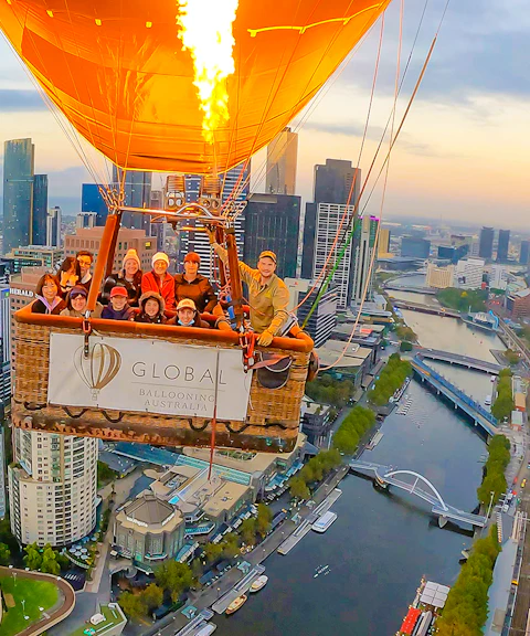 Hot air balloon over Melbourne cityscape at sunrise.