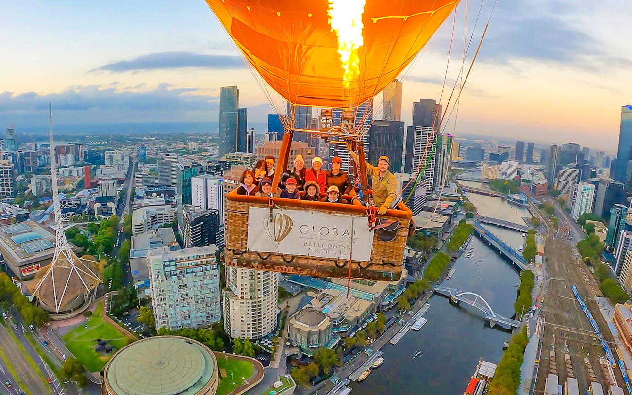 Hot air balloon over Melbourne cityscape at sunrise.