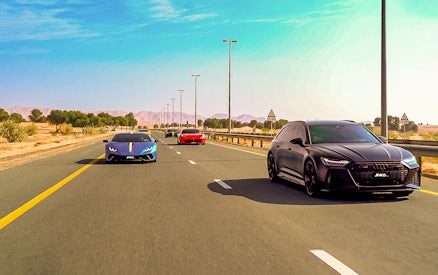 Supercars driving on a highway through the Dubai desert.