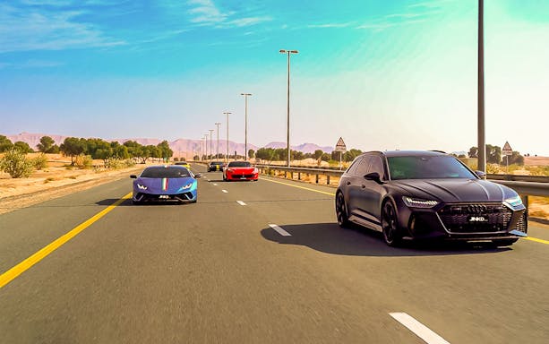 Supercars driving on a highway through the Dubai desert.