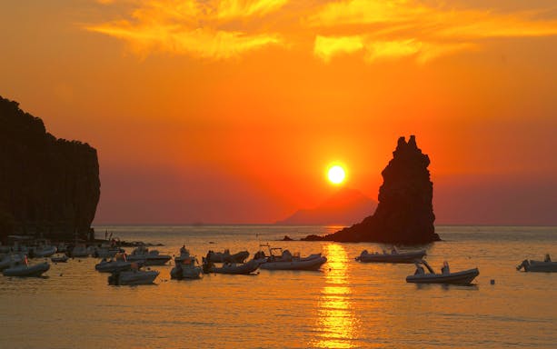 Boats on the water at sunset near Vulcano Island, Italy.