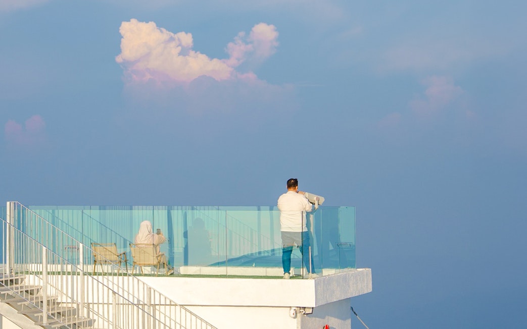 Tourist using binoculars at Hoverland Genting viewing platform.