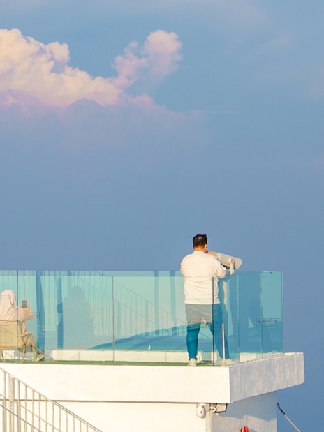 Tourist using binoculars at Hoverland Genting viewing platform.
