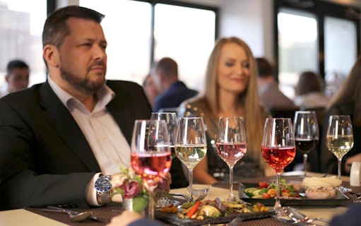 Wine glasses and gourmet dishes on a table during a Budapest cruise with live music.