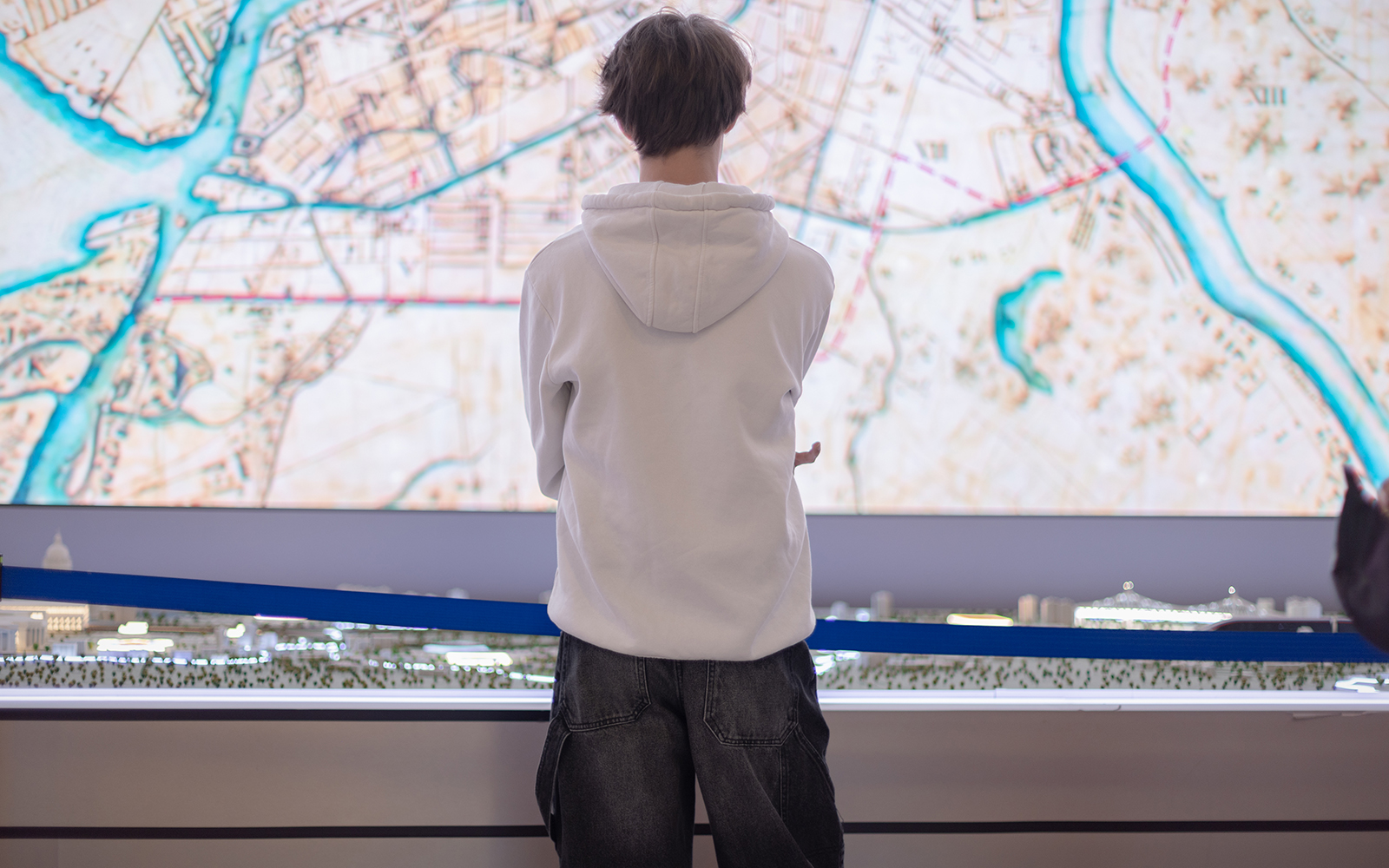 A male visitor stands in front of a miniature model of a city layout at the exhibition,
