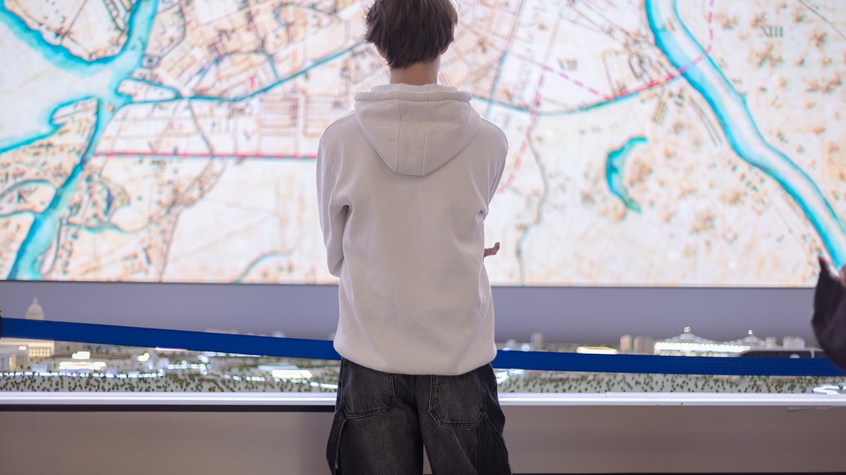 A male visitor stands in front of a miniature model of a city layout at the exhibition,