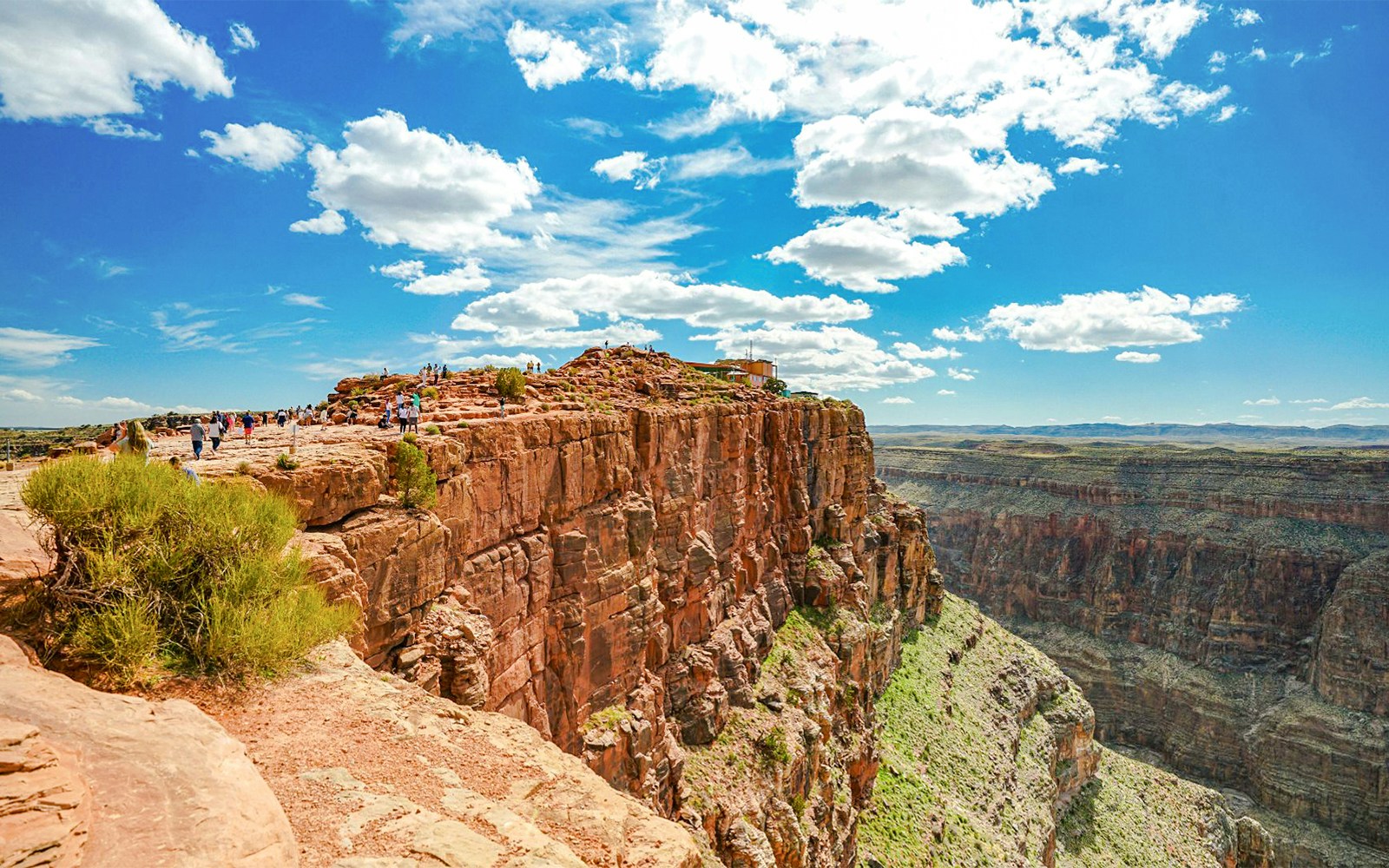 Guano Point view of Grand Canyon West with airplane flying over rugged canyon landscape.