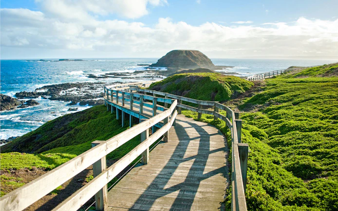 Coastal boardwalk at Phillip Island, Melbourne, with ocean and greenery.