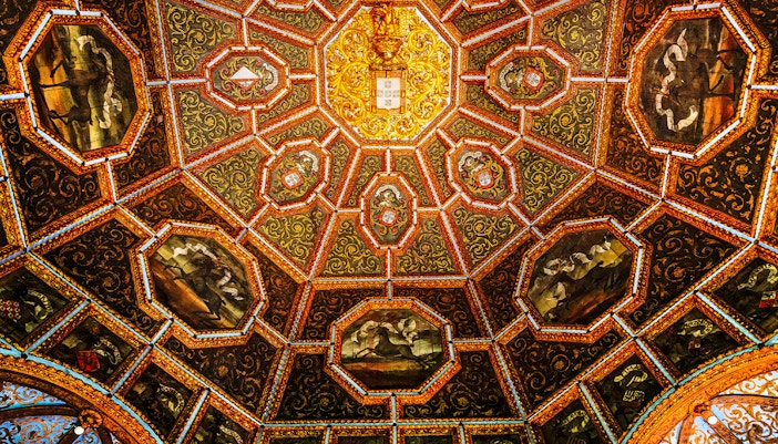Hall of Coats of Arms in National Palace of Sintra, Portugal, showcasing intricate ceiling and historical emblems.