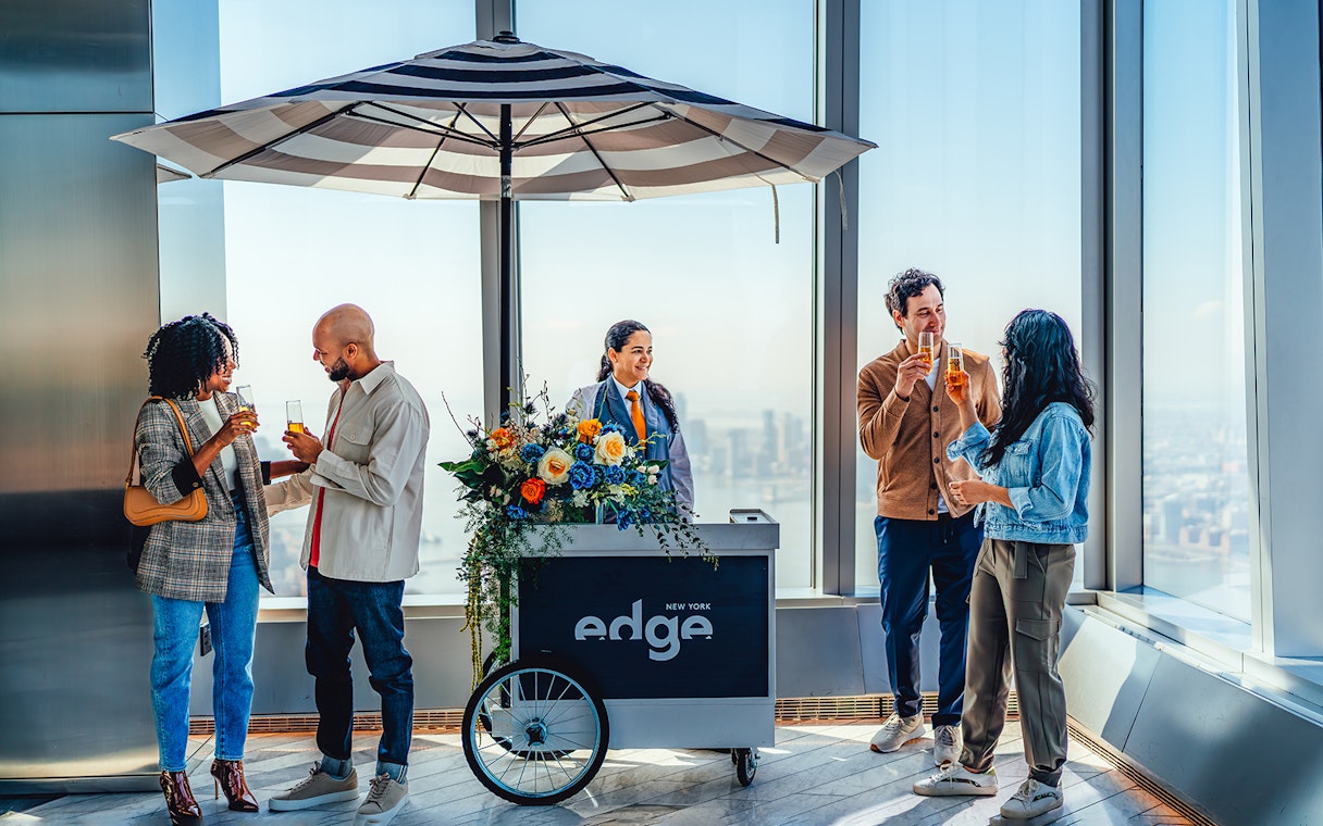Visitors enjoying drinks at Edge New York with city skyline view.