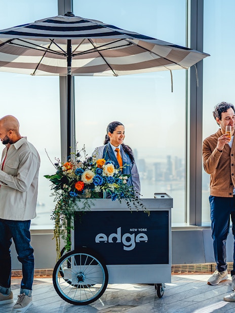 Visitors enjoying drinks at Edge New York with city skyline view.