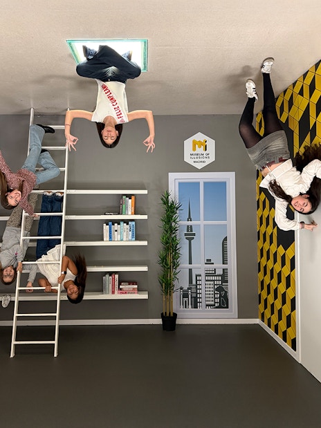 Visitors interacting with an upside-down room exhibit at the Museum of Illusions in Madrid.