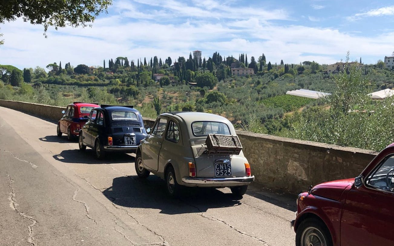 Vintage Fiat 500 cars on a scenic drive through the Tuscan countryside near Florence.