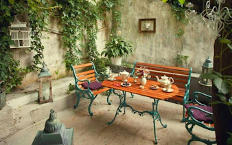 Outdoor cafe setting with tea set on a wooden table, surrounded by greenery in Cotroceni, Bucharest.