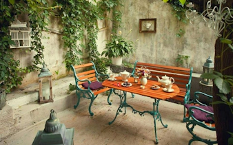 Outdoor cafe setting with tea set on a wooden table, surrounded by greenery in Cotroceni, Bucharest.