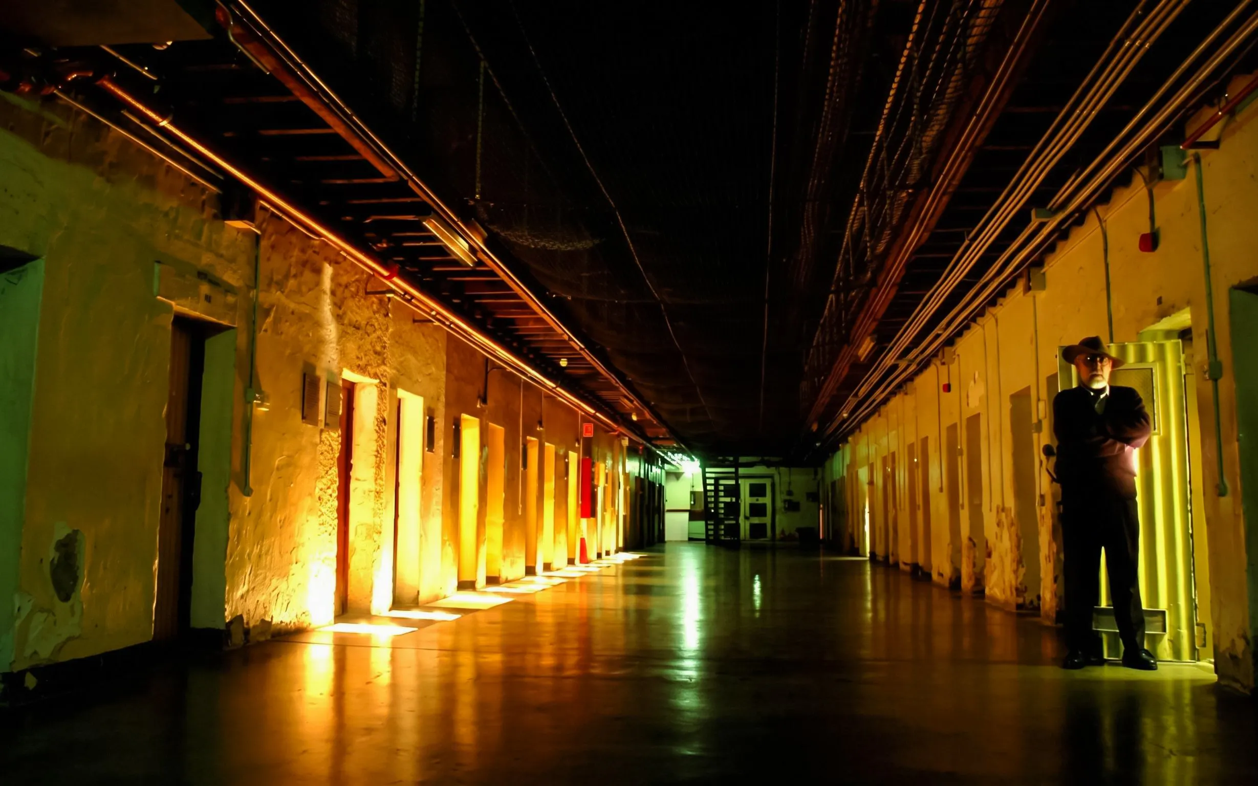 Corridor inside Fremantle Prison with guard standing by cell doors.