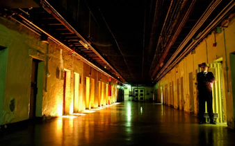 Corridor inside Fremantle Prison with guard standing by cell doors.