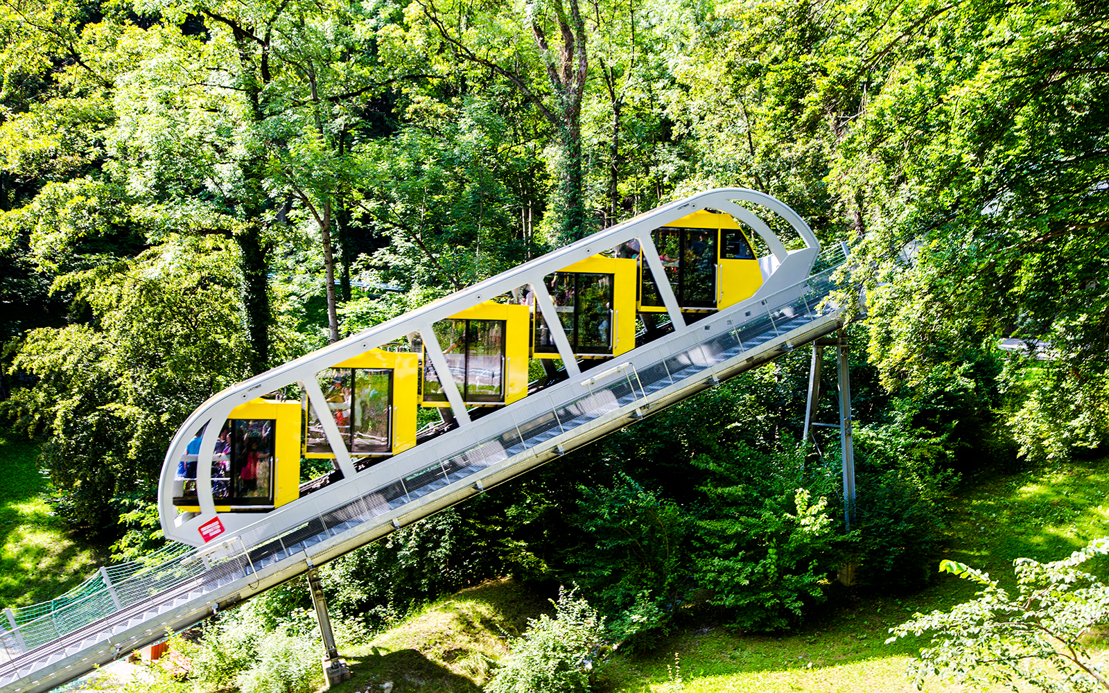 Hungerburg Funicular ascending through lush green forest in Innsbruck, Austria.