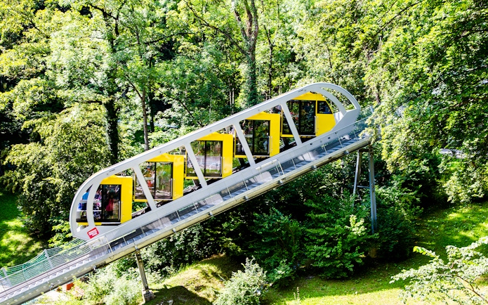 Hungerburg Funicular ascending through lush green forest in Innsbruck, Austria.