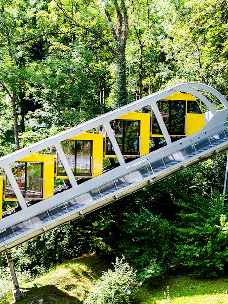 Hungerburg Funicular ascending through lush green forest in Innsbruck, Austria.