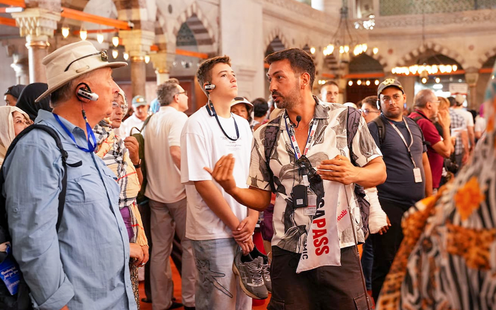 Guide leading a tour inside the Blue Mosque, Istanbul, with guests listening attentively.