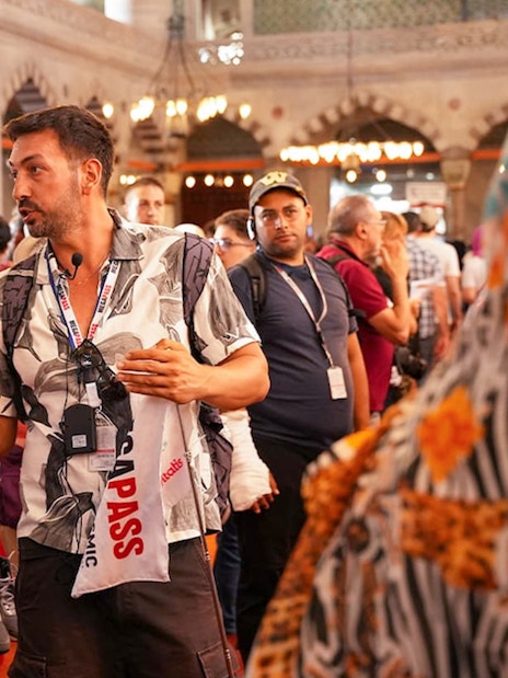 Guide leading a tour inside the Blue Mosque, Istanbul, with guests listening attentively.
