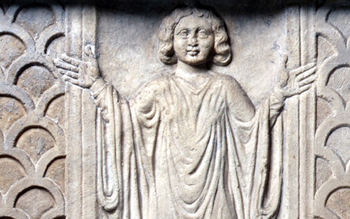 Stone relief of a figure with raised arms in the Catacombs of Saint Agnes, Rome.