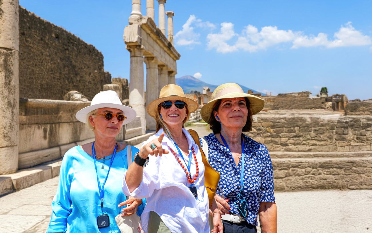 Female friends exploring ancient ruins at Pompeii with Mount Vesuvius in the background.