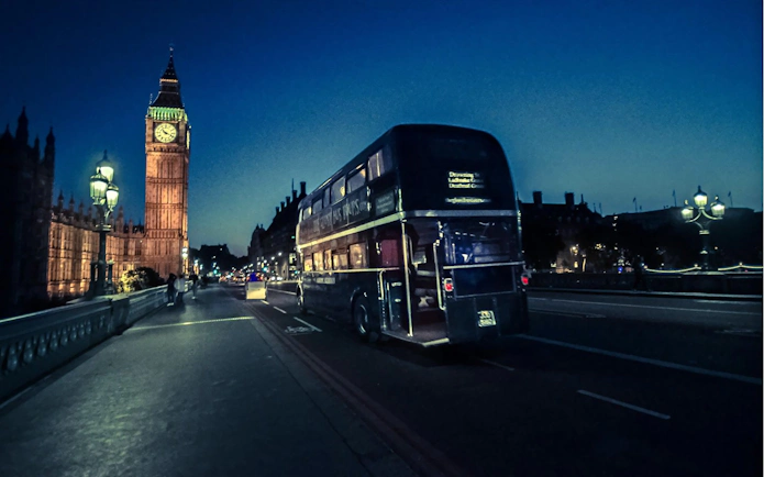 Double-decker bus on a London ghost tour passing Big Ben at night.