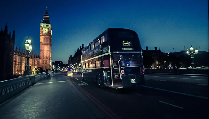 Double-decker bus on a London ghost tour passing Big Ben at night.