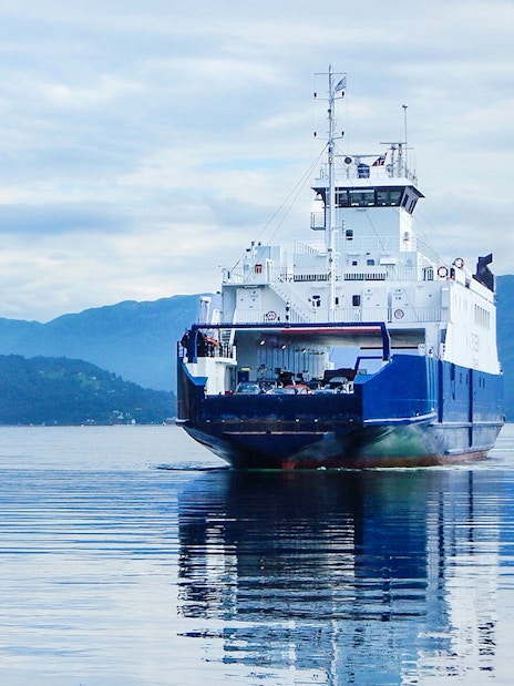 Ferry approaching dock on Hardangerfjord with mountains in the background.