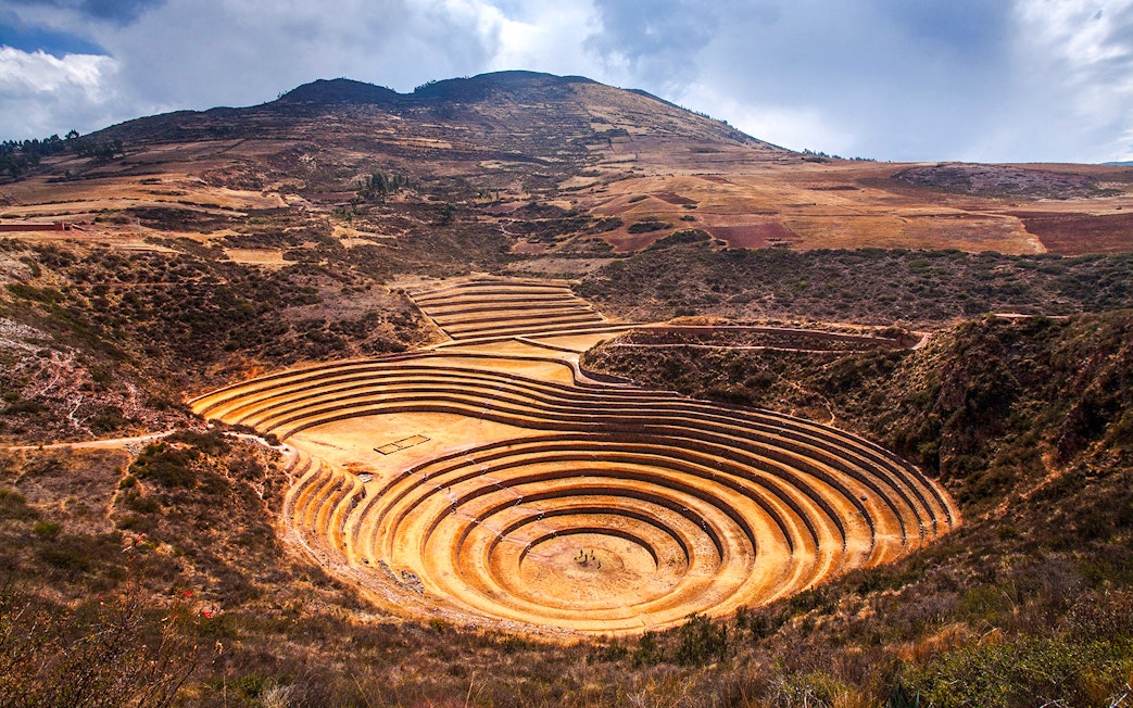 Moray archaeological site in Peru with circular terraces against a mountainous backdrop.