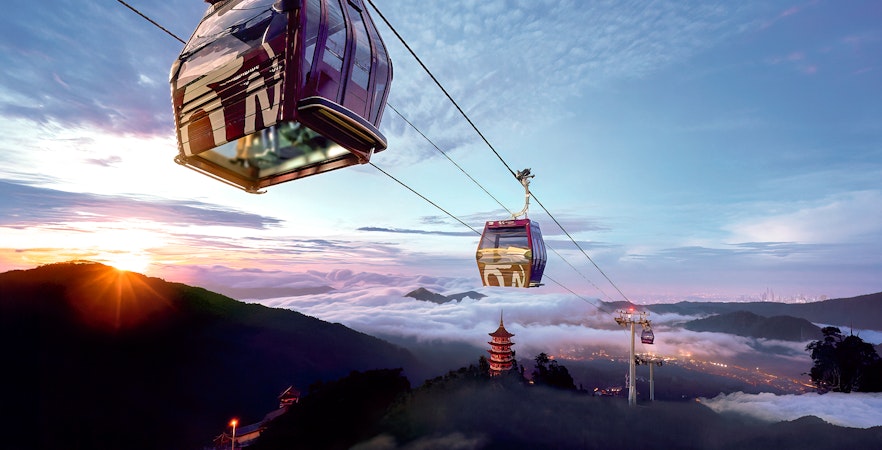 Genting Awana SkyWay cable car over misty mountains at sunrise.