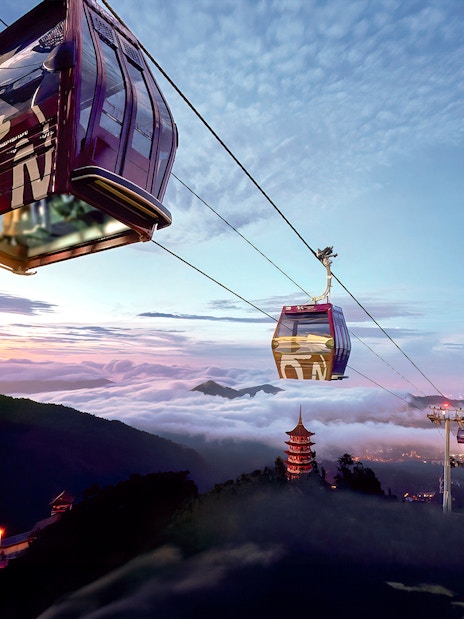 Genting Awana SkyWay cable car over misty mountains at sunrise.